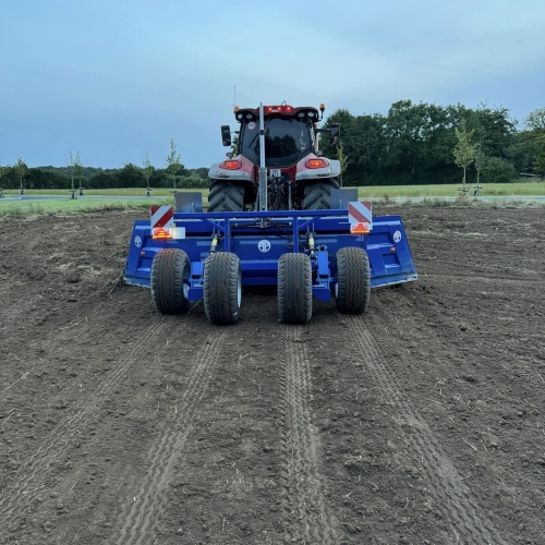 Traktor set bagfra, der arbejder med afretning af jorden på en åben mark