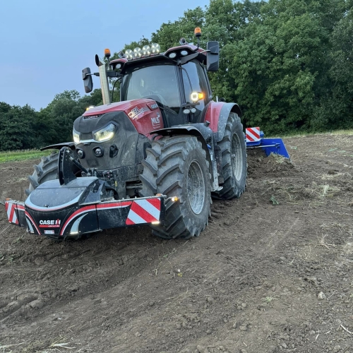 Traktor i gang med afretning af jord på en mark i forbindelse med et anlægsprojekt